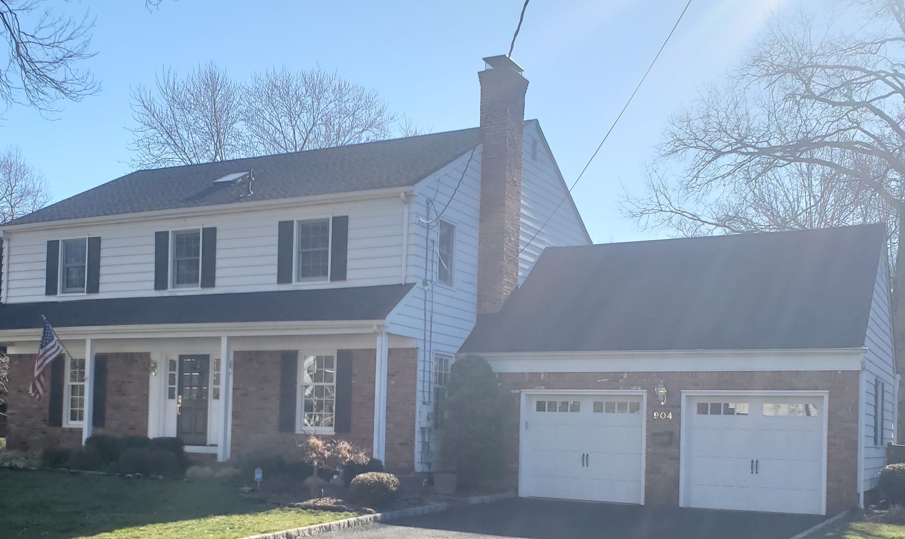 Front of the Westfield, New Jersey home before renovation — white clapboard over a brick first floor with a small flat-roofed entry and an attached two-car garage.